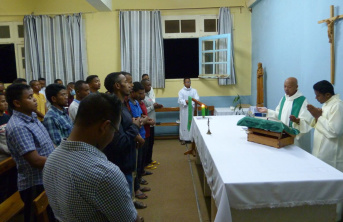 Hall filled with men receiving mass