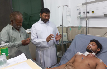 A Pakistani Father and a man standing over another man in a hospital bed giving prayer