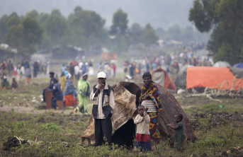 people in an open field with a tent and young children