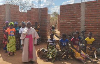 A priest and his congregation in front of a partially built wall