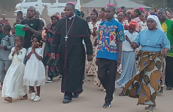 A priest and congregation walking on a road